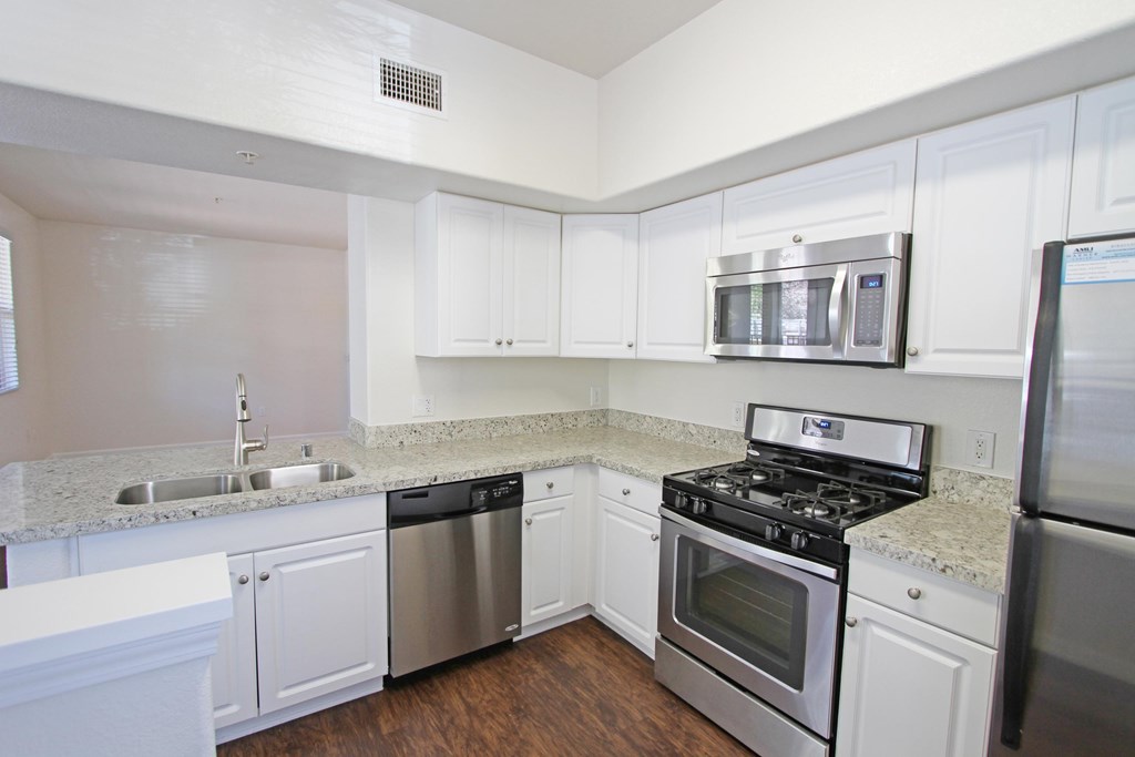 A kitchen with white cabinets and stainless steel appliances at The Kitt at Warner Center Apartments, California, 91303