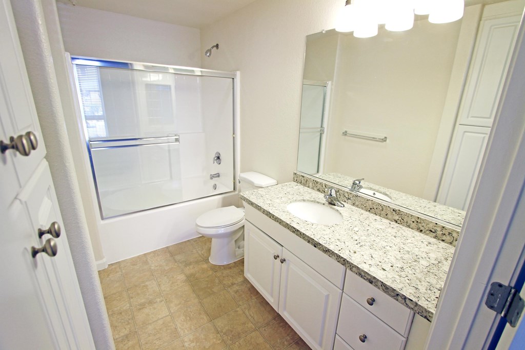 A bathroom with a toilet, sink, and mirror at The Kitt at Warner Center Apartments, California, 91303