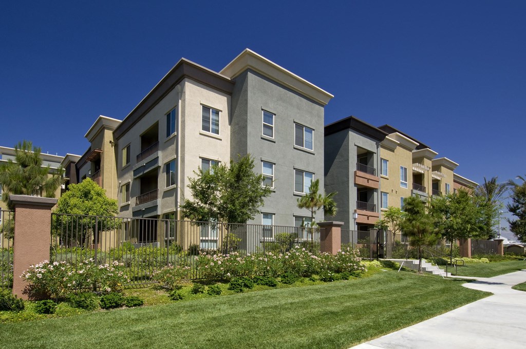 A row of modern apartment buildings with a well-maintained lawn in front. at The Kitt at Warner Center Apartments, California