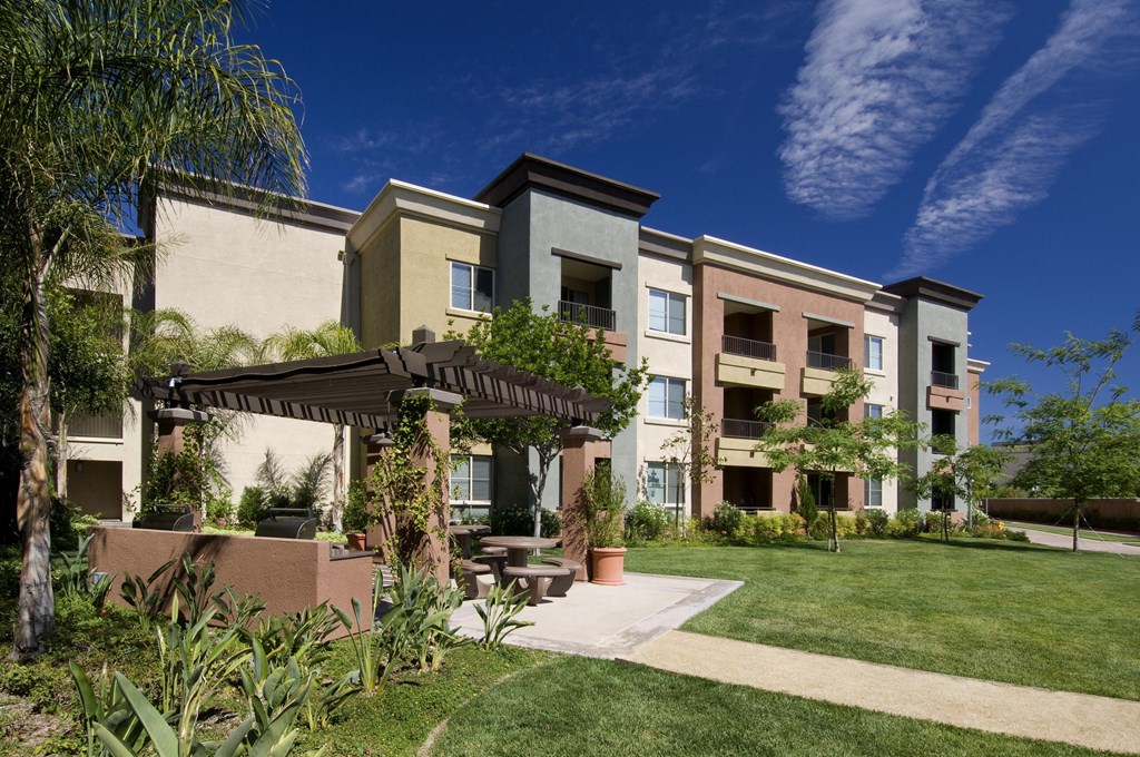 Apartment complex with a green lawn in front at The Kitt at Warner Center Apartments, California