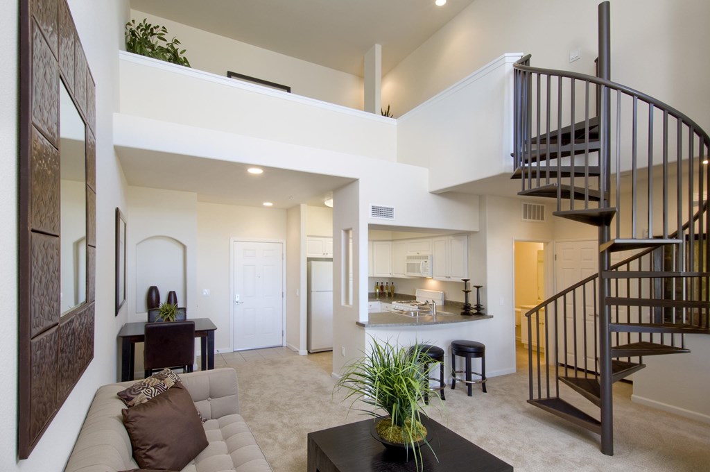 A living room with a couch, a coffee table, and a staircase. at The Kitt at Warner Center Apartments, Woodland Hills, CA, 91303