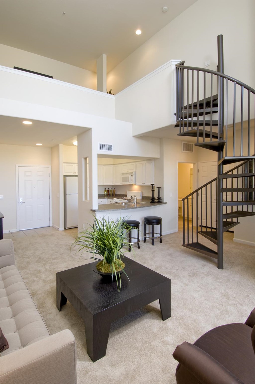 A living room with a spiral staircase and a coffee table at The Kitt at Warner Center Apartments, Woodland Hills 91303