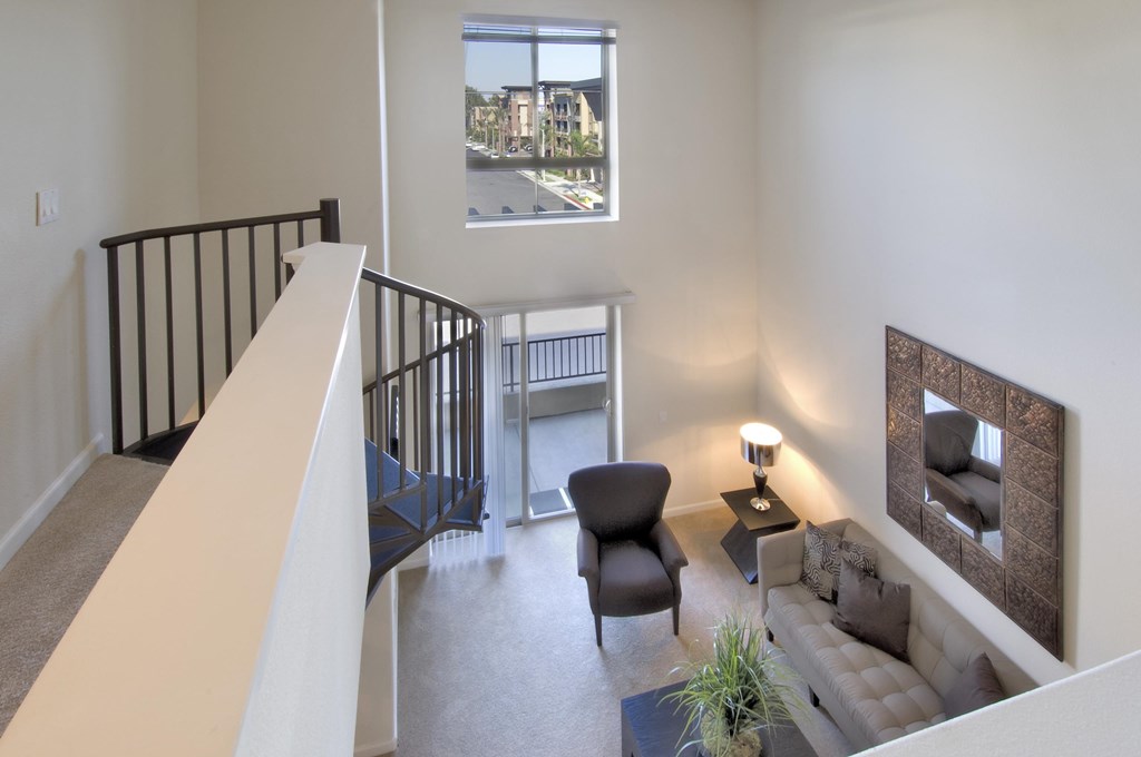 A living room with a couch, chair, and a small table with a lamp on it at The Kitt at Warner Center Apartments, Woodland Hills, CA