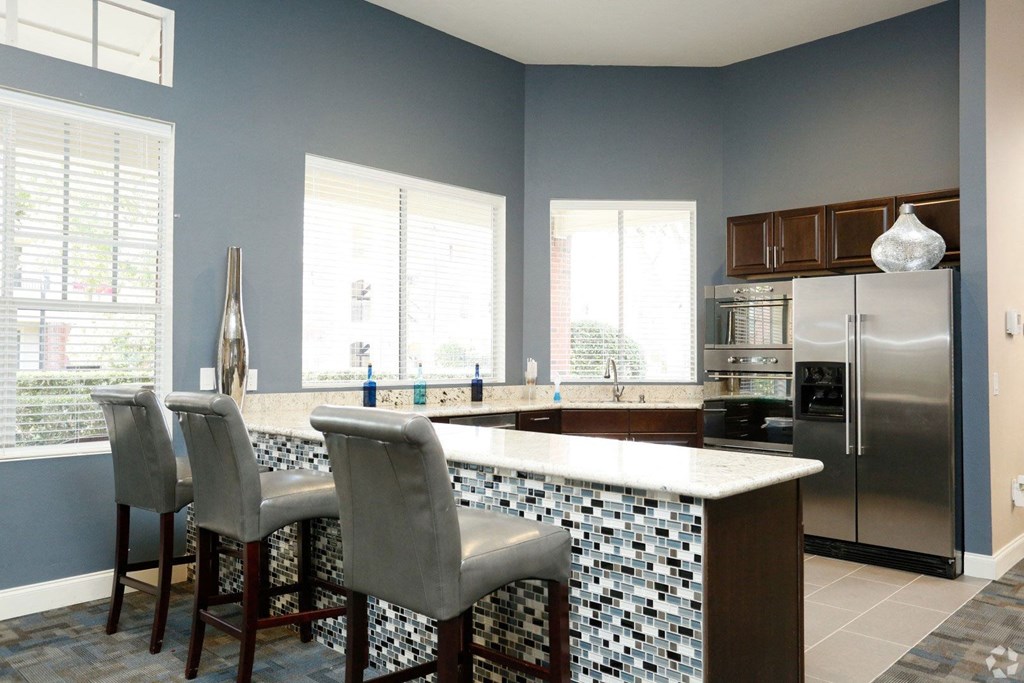 a kitchen with a bar and a stainless steel refrigerator at Veranda at Centerfield, Houston, TX