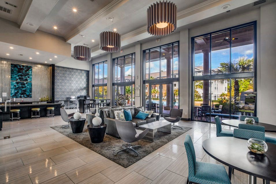 a lobby with chairs and tables and large windows