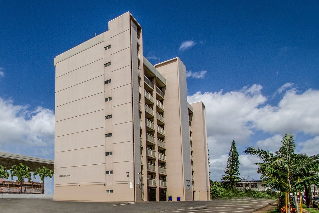 a large white building with a blue sky in the background at Waikele Towers Apartments, Waipahu, HI