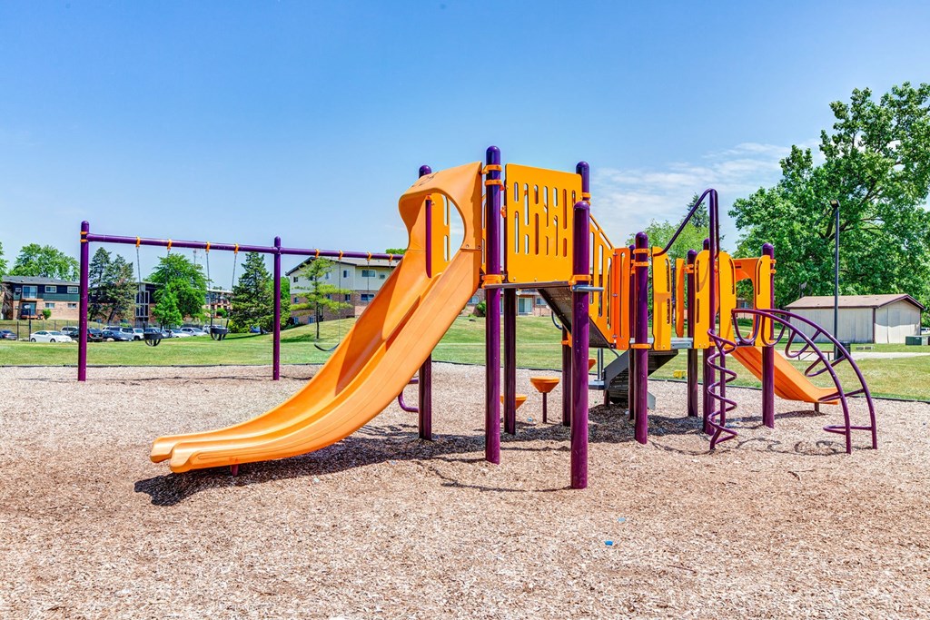 a playground with a yellow slide and other playground equipment at Willow Hill Apartments, Justice, IL