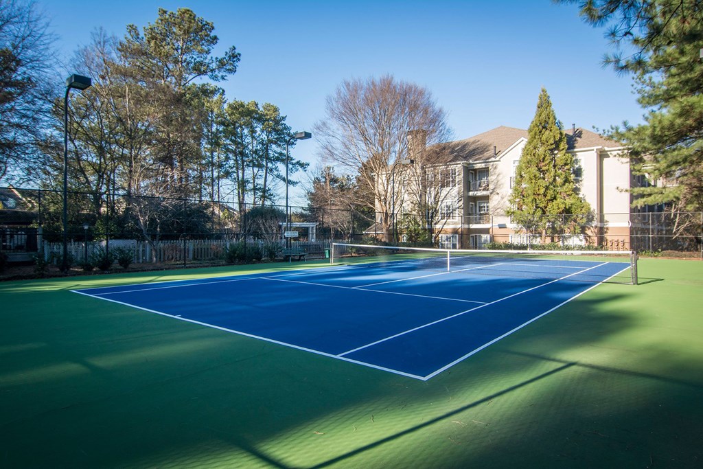 a tennis court with a house in the background a tennis court with a house in the background at Willowest in Lindbergh, Atlanta, Georgia