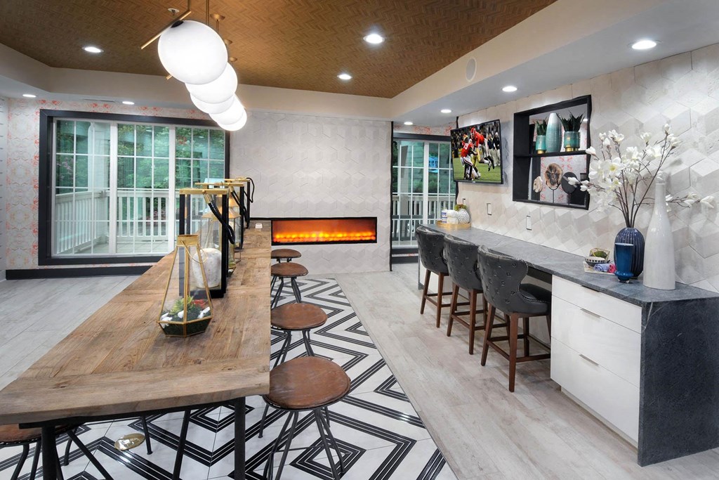 a dining room with a long wooden table and a kitchen with a fireplace