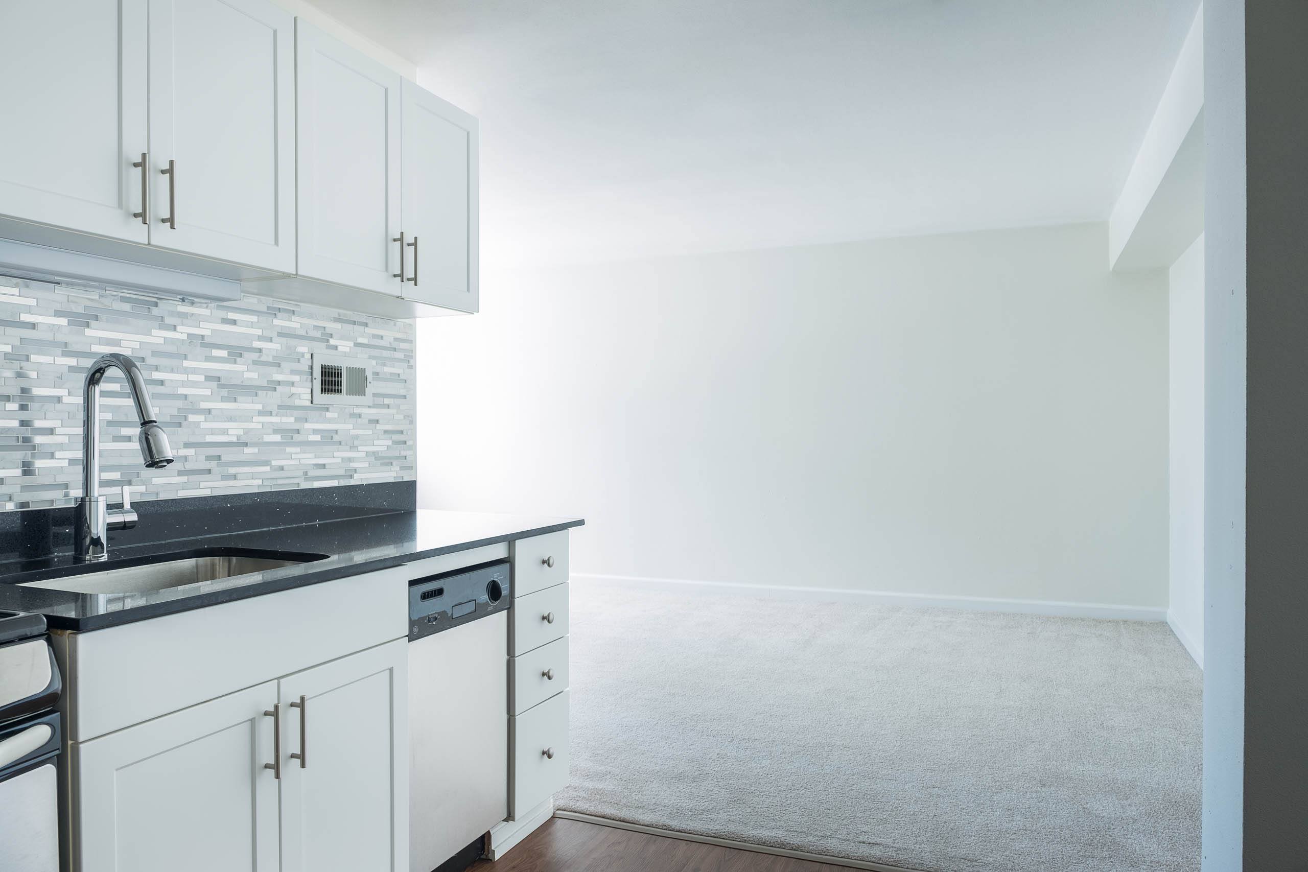 A kitchen with white cabinets and a grey countertop.