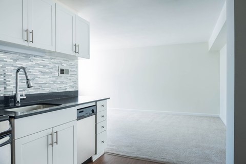 A kitchen with white cabinets and a grey countertop at Skye at Belltown Apartments, Seattle, Washington