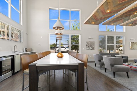 a dining area with a table and chairs and large windows at Ridge at Thornton Station Apartments, Colorado