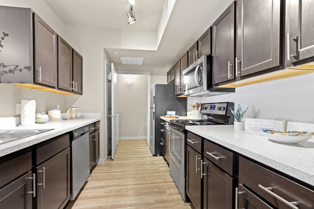 a large kitchen with stainless steel appliances and white counter tops at Ridge at Thornton Station Apartments, Thornton