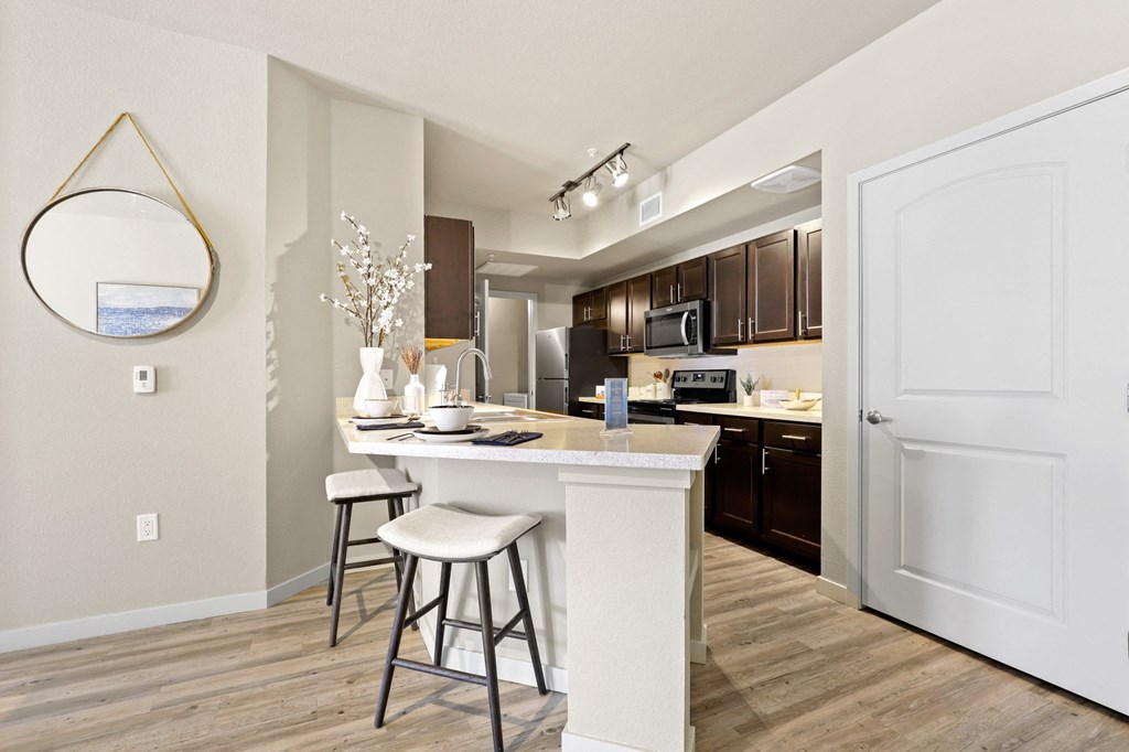 a kitchen with a bar and stools in a renovated apartment at Ridge at Thornton Station Apartments, Thornton, CO