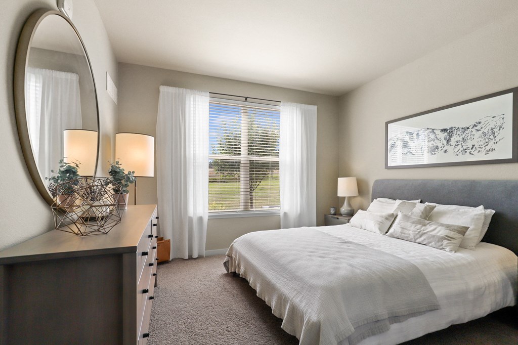 a bedroom with a large bed and a mirror at Ridge at Thornton Station Apartments, Colorado, 80229