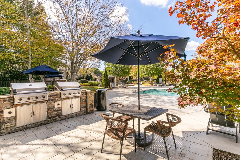 a patio with an umbrella and chairs and a swimming pool at Roswell Village, Roswell, Georgia