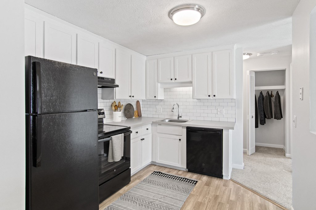 a renovated kitchen with black appliances and white cabinets  at Rosemont Square Apartments, Randolph