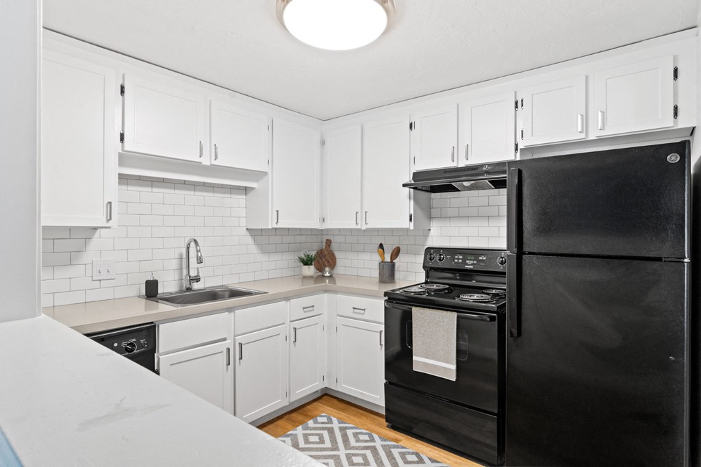 a kitchen with black appliances and white cabinets at Rosemont Square, Randolph, Massachusetts