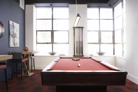 A pool table is in the middle of a room with a bar and a window at Skye at Belltown Apartments, Washington 98121