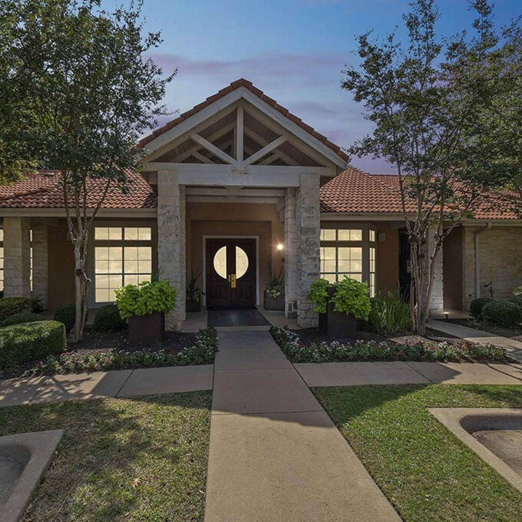 the front entrance of a home with a walkway and grass