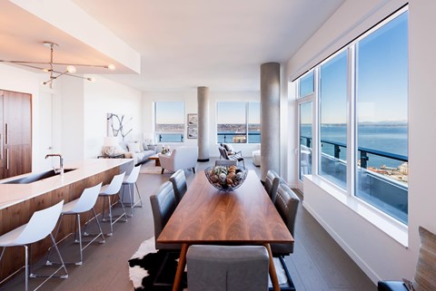 A modern dining room with a long wooden table and chairs.