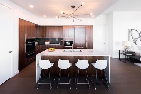 A modern kitchen with a long white table and white chairs.