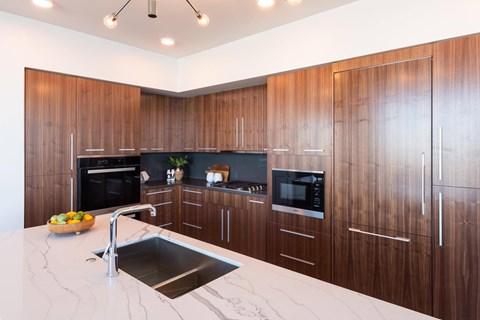 A modern kitchen with wooden cabinets and a marble countertop.