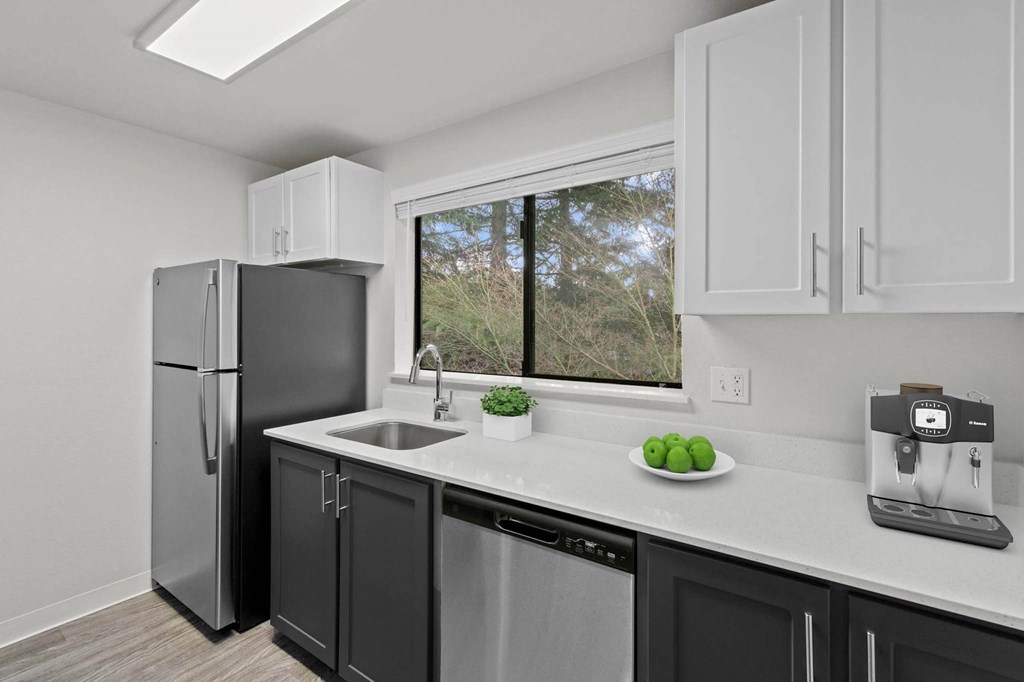 A kitchen with a black fridge and a white counter at Brackett Apartments, Edmonds