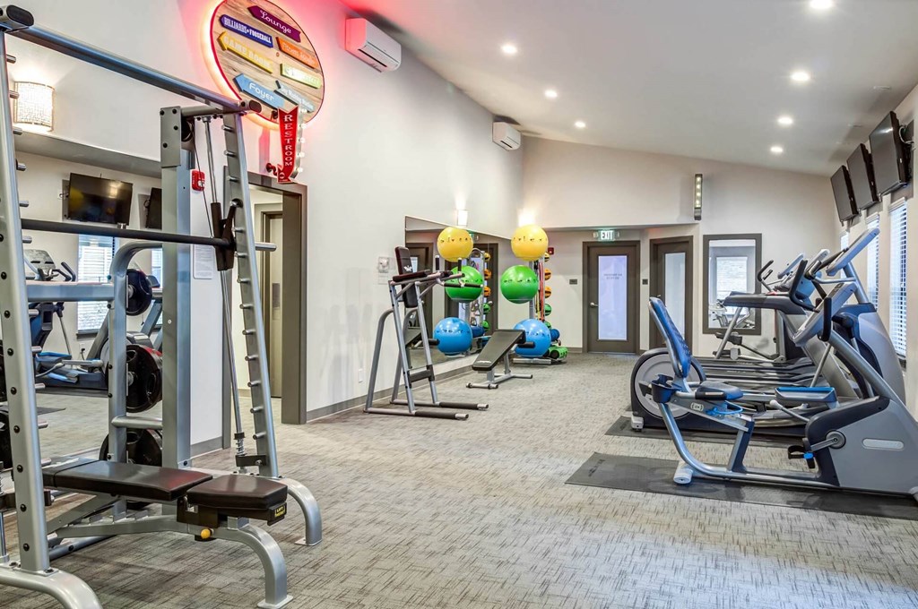 A gym with a variety of equipment including treadmills, weights, and exercise balls at Brackett Apartments, Edmonds, WA