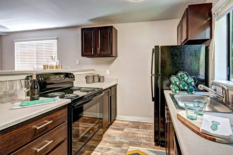 A kitchen with a black refrigerator and wooden cabinets.