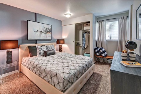A bedroom with a large bed with a grey quilted duvet cover and a painting on the wall at Brackett Apartments, Edmonds, 98020