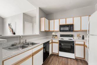 a kitchen with white cabinets and black appliances at Veranda at Centerfield, Houston, TX