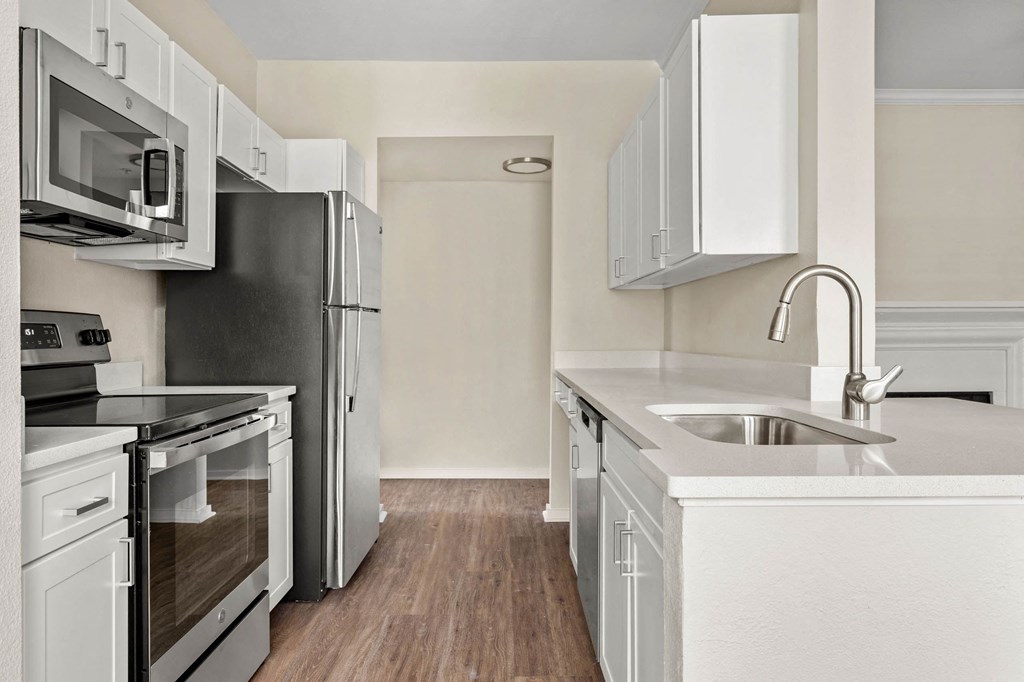 a renovated kitchen with white cabinets and stainless steel appliances at Villages of Cypress Creek, Texas, 77070