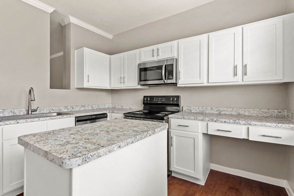 a kitchen with white cabinets and granite counter tops at Villages of Cypress Creek, Texas, 77070