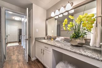 a bathroom with a large mirror and a counter with yellow flowers at Creekside at Legacy, Plano, TX