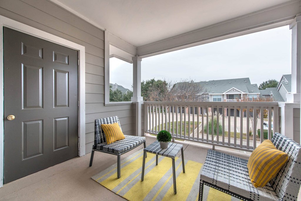 a covered porch with two chairs and a door to a balconyat Creekside at Legacy, TX 75024