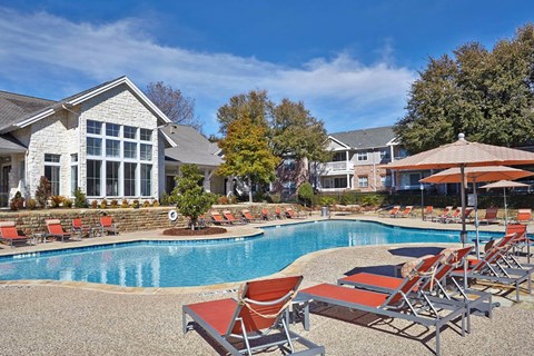 a swimming pool with chairs and umbrellas in front of a houseat Creekside at Legacy, Plano, TX