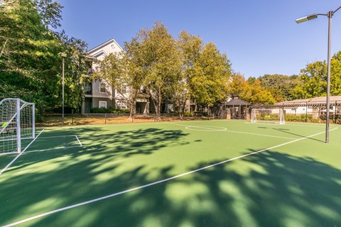 a tennis court with trees and a house in the background at Deerfield Village, Georgia