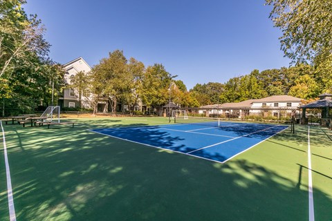a tennis court with trees and a house in the background at Deerfield Village, Alpharetta, Georgia