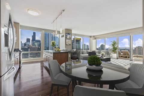 A modern kitchen with a table and chairs and a view of the city.