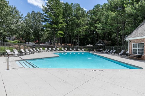 a swimming pool with chairs around it and trees in the background at Gwinnett Pointe, Georgia, 30093