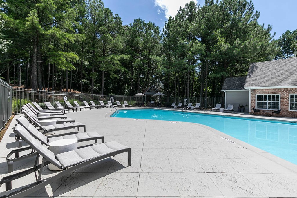 a swimming pool with lounge chairs next to a resort style pool at Gwinnett Pointe, Norcross