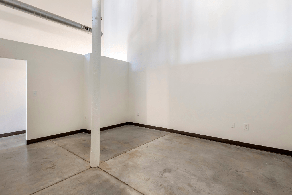 an empty room with white walls and a concrete floor and a pole at Highland Mill Lofts, North Carolina