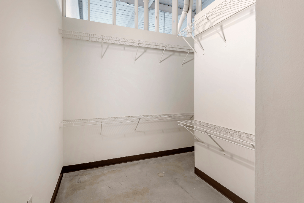 a room with white walls and a window and a closet with white shelves and racks at Highland Mill Lofts, North Carolina, 28205