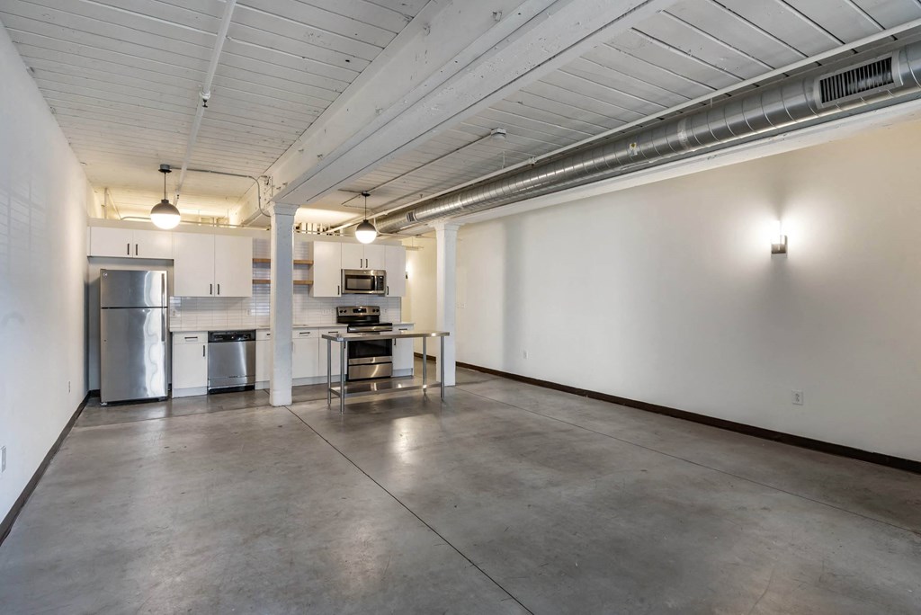 an empty room with a kitchen and a table in the middle at Highland Mill Lofts, Charlotte, North Carolina