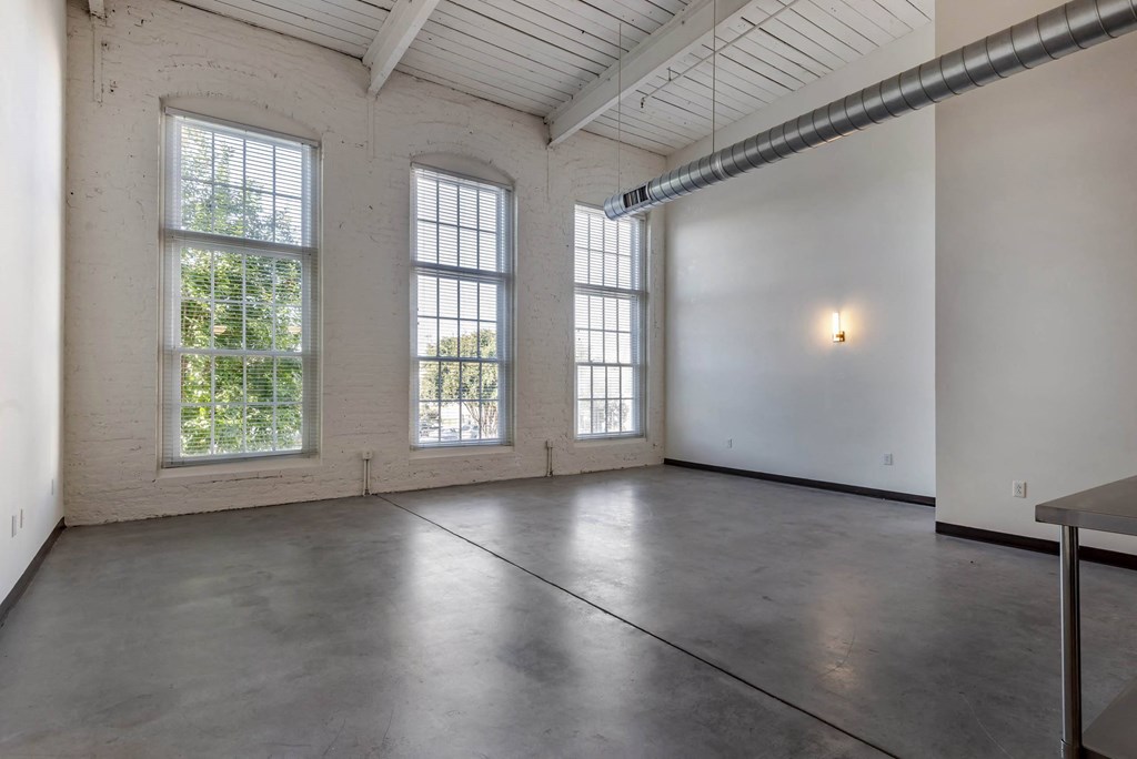 an empty room with three large windows and a table at Highland Mill Lofts, Charlotte, NC