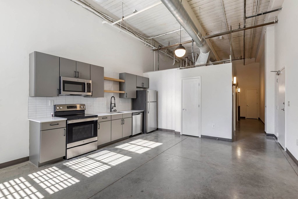 a kitchen with stainless steel appliances and white walls at Highland Mill Lofts, Charlotte
