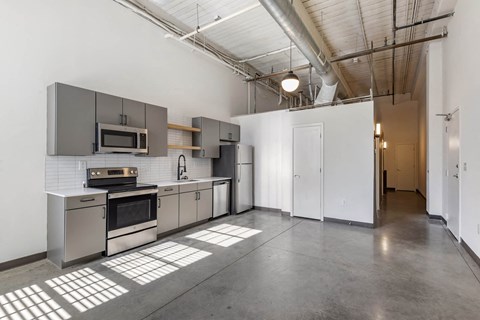 a kitchen with stainless steel appliances and white walls at Highland Mill Lofts, Charlotte