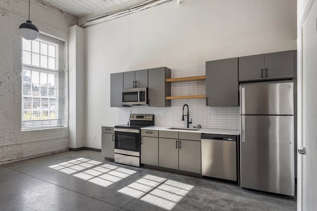 a kitchen with stainless steel appliances and a window at Highland Mill Lofts, Charlotte, North Carolina