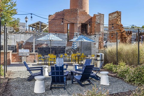a patio with blue and yellow chairs and umbrellas at Highland Mill Lofts, Charlotte, North Carolina